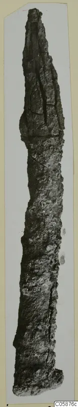Long, pointed iron weapon, heavily corroded, photographed upright against a pale card