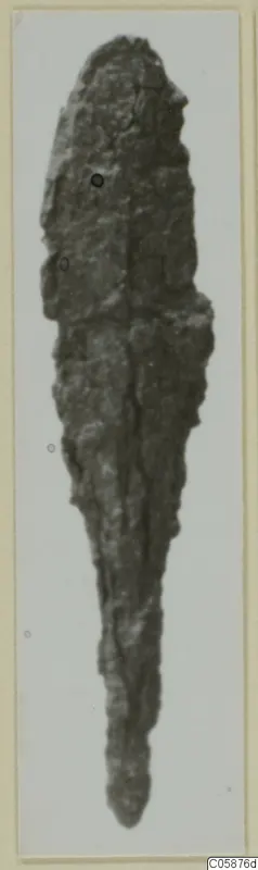 Corroded iron weapon from Idalion: a long, tapering blade shown on a pale card mount.