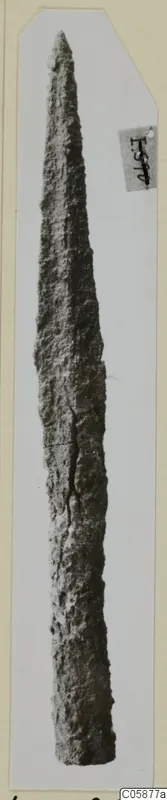Iron weapon with a long pointed blade, its surface rough and corroded, shown upright on a card mount