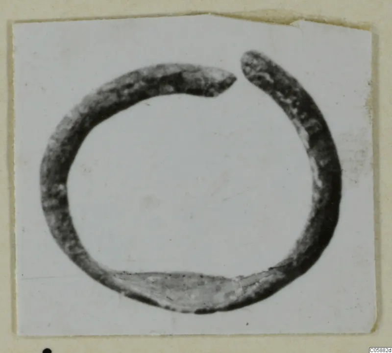 Open bronze ring with a gap at the top, photographed on a card mount.