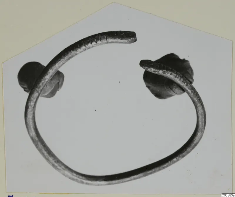 Bronze bracelet from Idalion, an open ring with knob-shaped ends, photographed on a pale background.