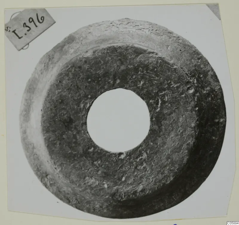 Ring-shaped metal object with a large central hole and a corroded, pitted surface.