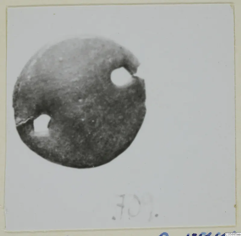 Bronze mounting fragment: a flat disc with two round holes near its edge