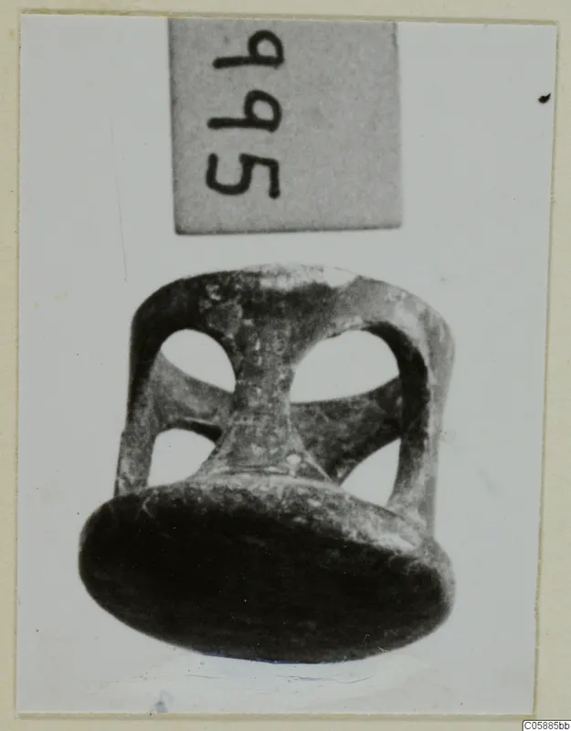 Bronze openwork mounting with a flat disc base and round openings in its sides, photographed against a light background.