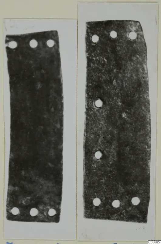 Two flat dark metal strips with rows of rivet holes, bronze mountings and fragments from Idalion