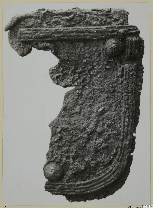 Corroded metal fragment with ribbed moulding and two rounded knobs