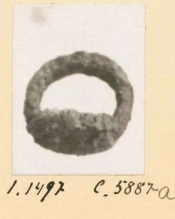 Corroded dark metal ring from Idalion, shown on a small mounted photograph