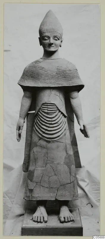 Terracotta statue of a standing figure in a tall conical hat and ridged cape, on a wooden base