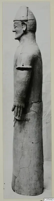 Terracotta statue of a standing figure in side view, with a close-fitting cap and one arm bent at the waist.