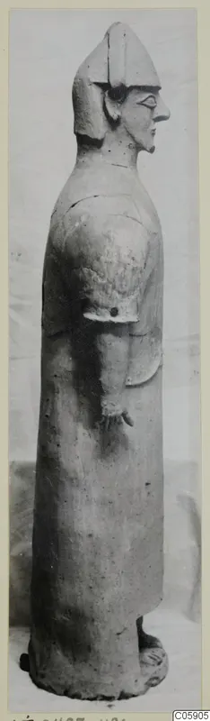 Terracotta standing figure seen in profile, with a helmet-like headdress and long robe, from Ayia Irini
