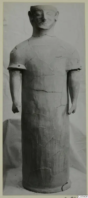 Terracotta statue of a standing figure with a cylindrical body, short arms and a rounded head