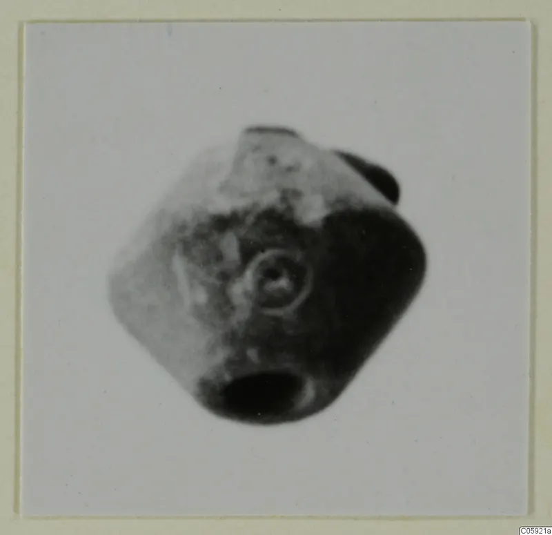 Blurred photograph of a small faceted object with a ringed circular motif on one face, a small find from Idalion