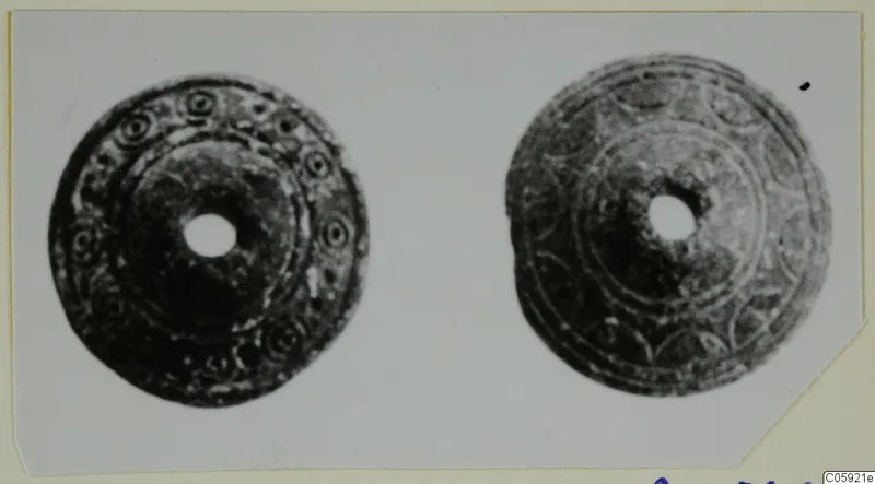 Two round disc-shaped objects with central holes, decorated with concentric rings and small circular motifs.
