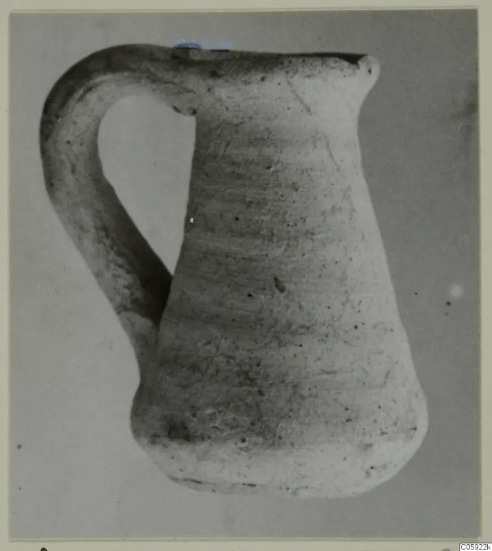 Plain white pottery jug with a loop handle, seen from the side