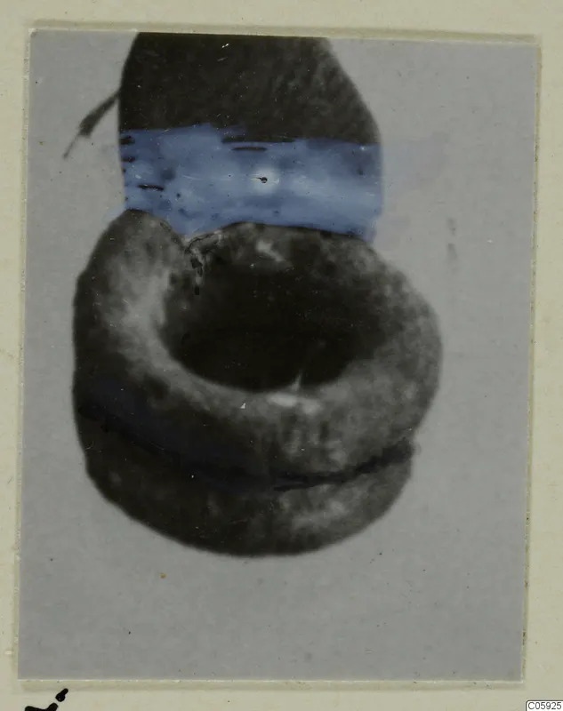 Silver earring, a ring-shaped object, photographed against a grey card mount.