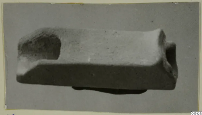 Faience spout, a small rectangular object shown in side view with a hollow opening at one end.