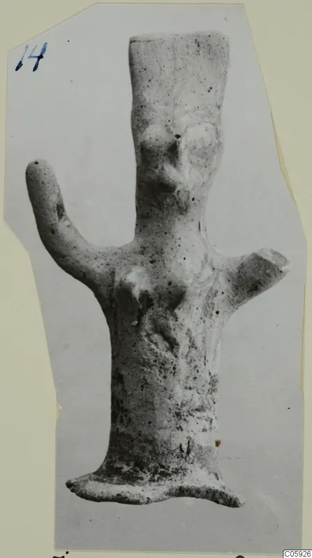 Terracotta figurine with a tall body, one arm raised and a flat base, mounted on a card