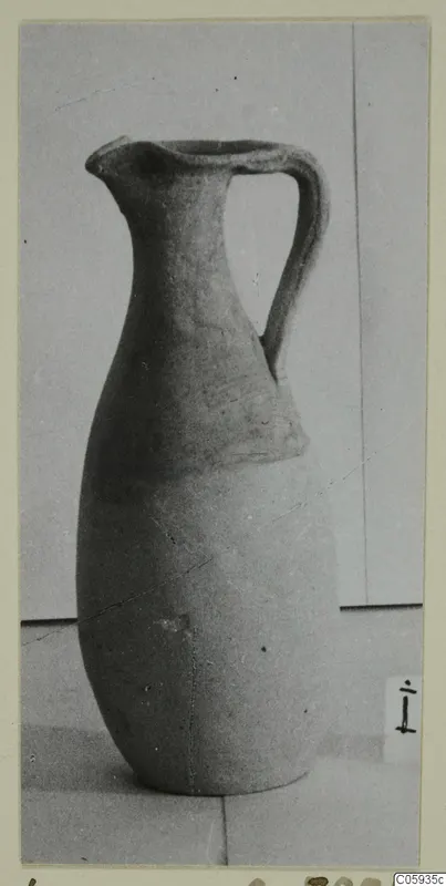 Pottery jug with a single strap handle and pinched spout, photographed on a plain surface