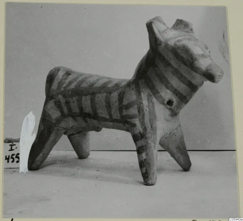 Terracotta figurine of a four-legged animal with dark painted stripes on its body and legs