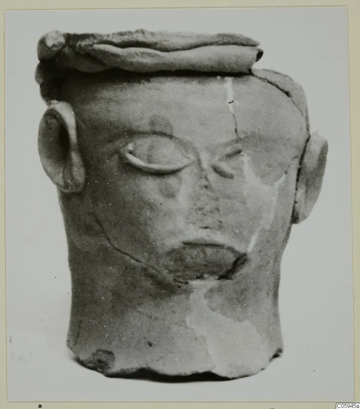 Terracotta head-shaped object from Ayia Irini, with relief eyes, mouth and ears, photographed on a card mount