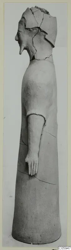 Terracotta figure of a standing human figure, broken at the head, with one arm extended forward.