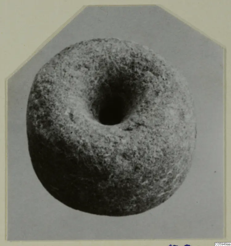 Round object with a large central hole, shown in a photograph mounted on a card