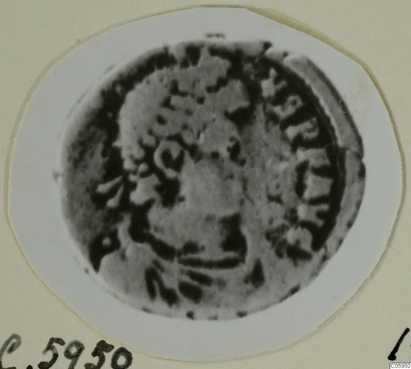 Worn bronze coin from Idalion, photographed close up on a white oval card mount.