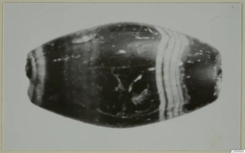 Oval banded bead with a dark glossy body and pale stripes, small find from Idalion
