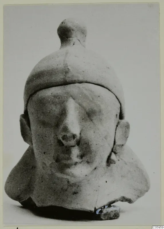 Terracotta bust of a man from Ayia Irini, shown frontally with a tall capped head and a prominent nose.