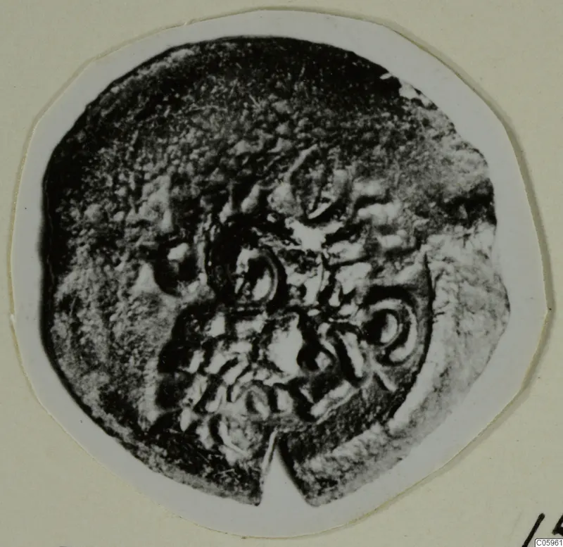 Round corroded object with raised circular and curled motifs, shown on a mounted card; find from Idalion.