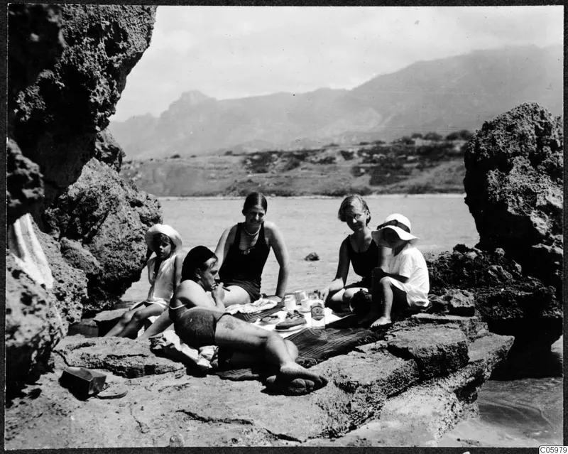 Five people picnicking on a rocky shore at Kyrenia, with the sea and mountains behind