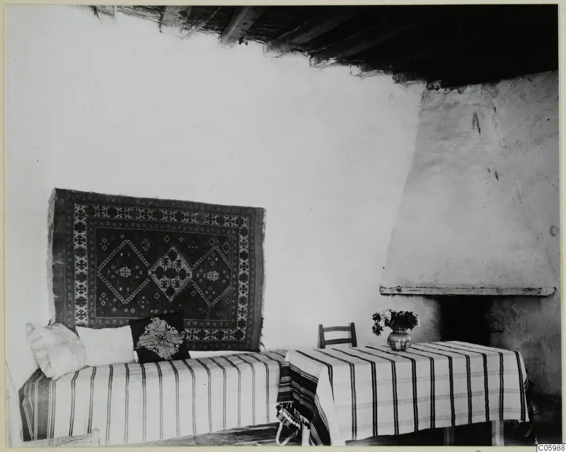 Interior with a striped sofa or bed, a hanging rug and a white fireplace at Machairas
