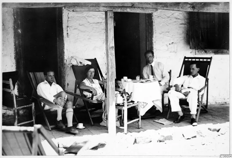 Four people rest on deckchairs and beside a tea table on a whitewashed terrace at Machairas.