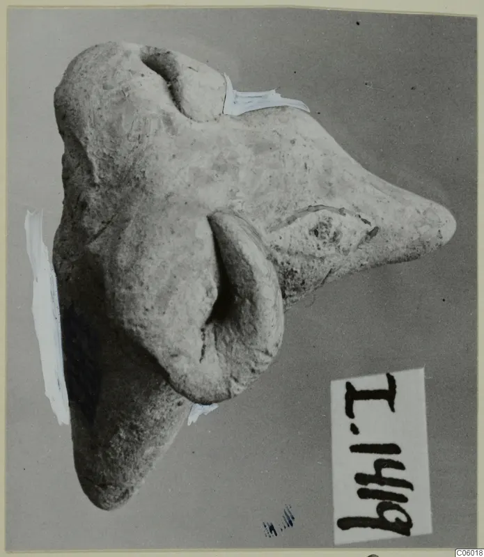 Terracotta minor plastic animal figurine on a grey backdrop, photographed sideways