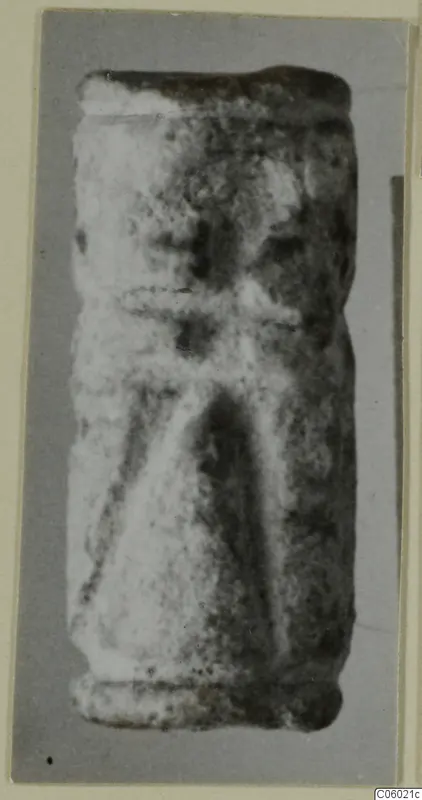 Cylinder seal standing upright, with a worn surface and faint incised lines.