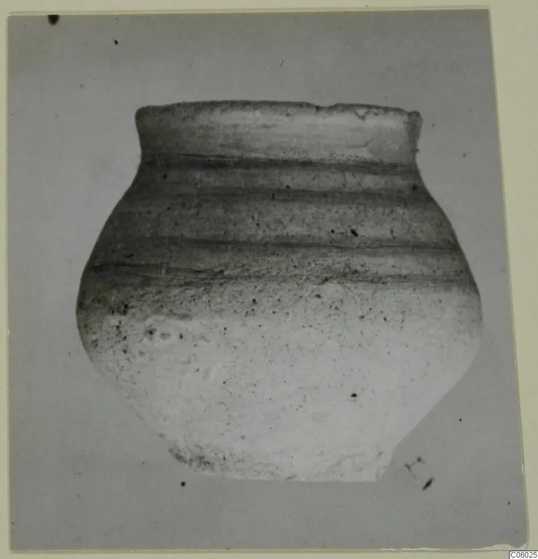 Pottery jar with a short flaring neck and dark horizontal bands, photographed against a plain grey background
