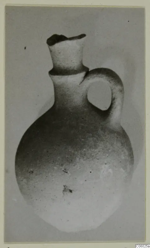 Small round-bodied jug with a tall neck and a loop handle, shown against a plain grey background.