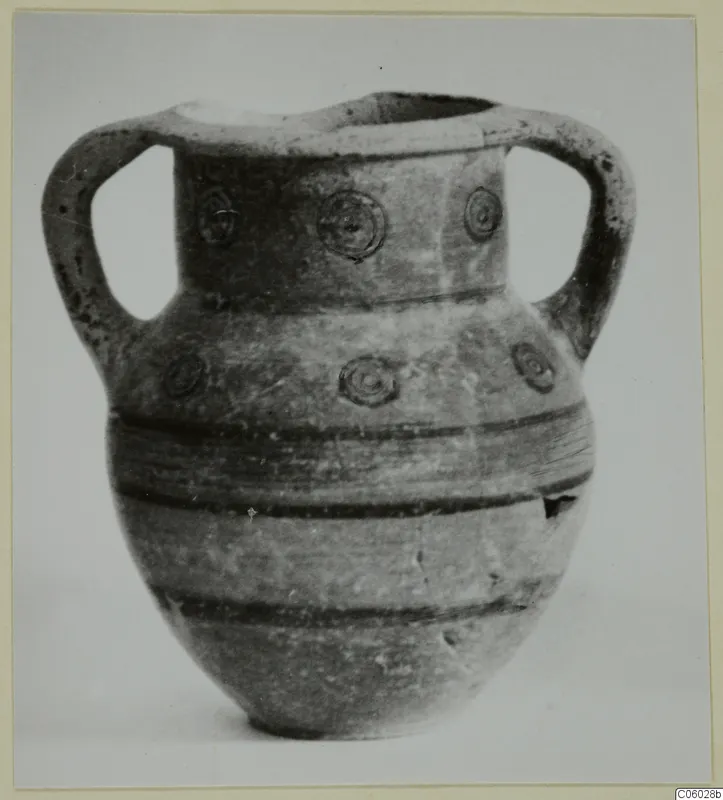 Two-handled pottery vessel with concentric circle motifs on the neck and shoulder and dark horizontal bands on the body.