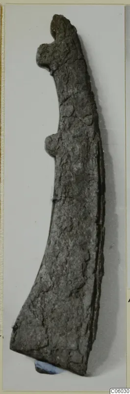 Corroded iron tool from Idalion with a hooked upper end and a curved, widening blade