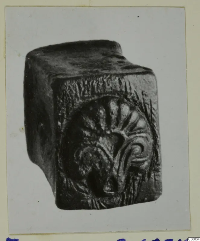 Bronze tools from Idalion: a dark block-shaped object with a raised fan-shaped motif on one face