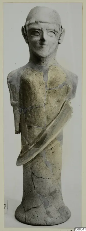 Terracotta statuette of a standing figure with a rounded head, repaired after breakage, photographed against a pale background.
