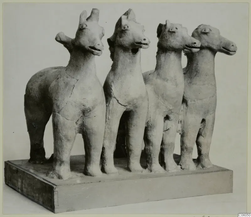 Four terracotta animal figurines standing in a row on a wooden base, Mersinaki