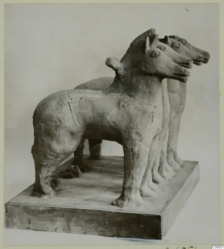 Terracotta group of three standing animals with pointed ears on a rectangular plinth, photographed from the front left.
