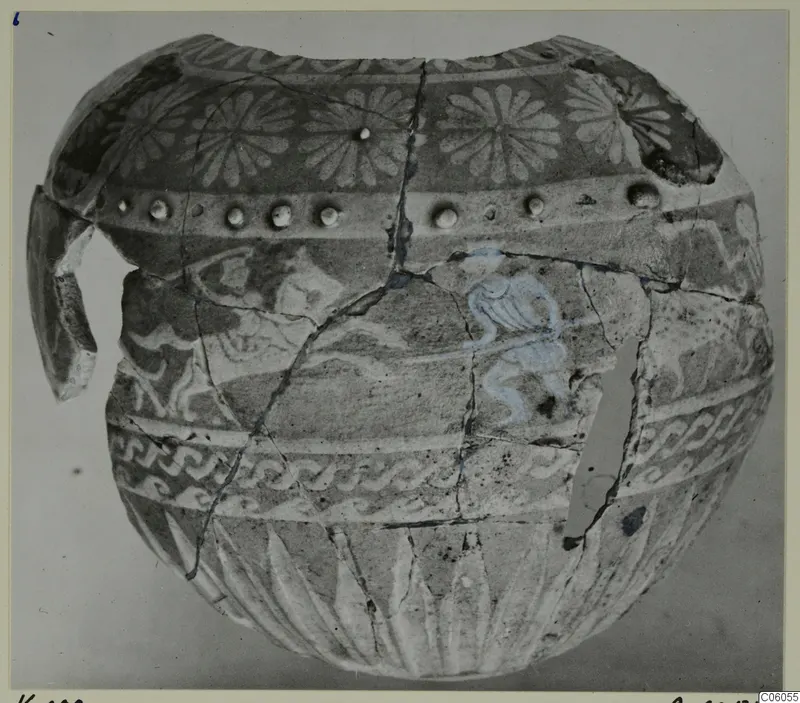 Faience jug, reconstructed from fragments, with painted rosettes, spiral bands and a blue-tinted motif
