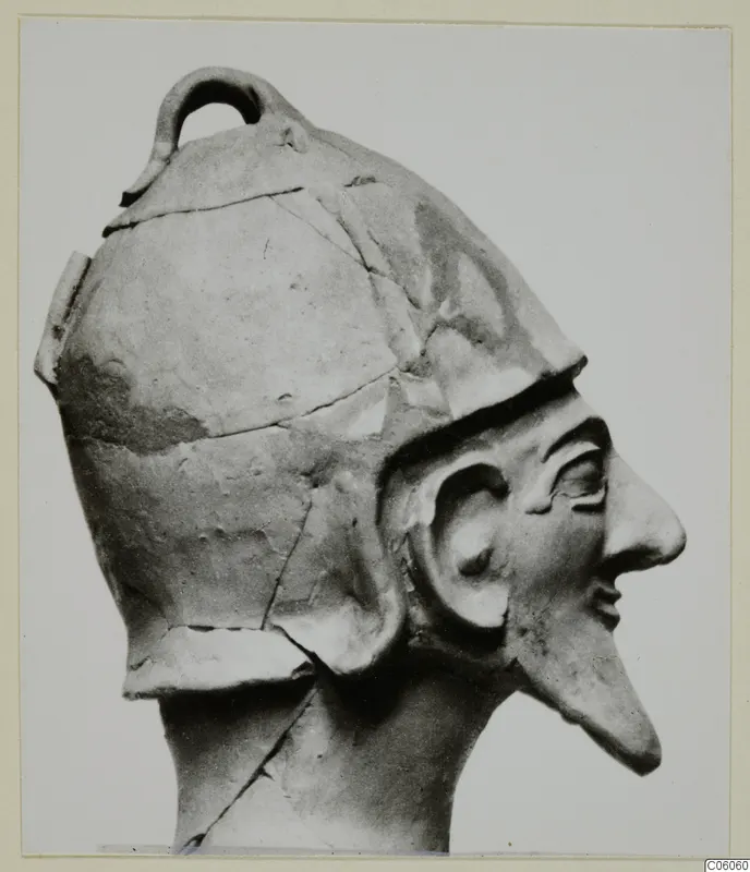 Terracotta head of a statue from Ayia Irini, shown in profile, wearing a helmet-like cap with a loop on top.