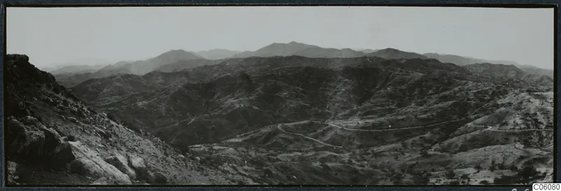 Vouni: view south over hilly country, with a winding road and a rocky outcrop in the foreground
