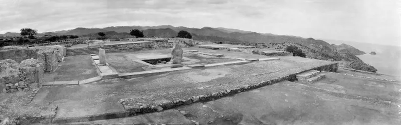 Central court of the Vouni palace ruins, paved, with a standing column and stone steps, hills and sea beyond.