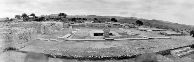 Central court at Vouni with a large stone vessel, a stepped terrace, cut-stone walls and hills in the distance
