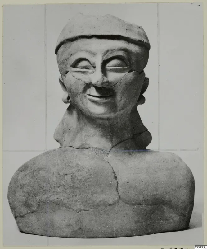 Terracotta bust of a smiling figure in a close-fitting cap, cracked and broken at the neck