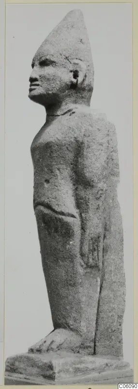 Limestone Cypro-Egyptian standing figure in profile, facing left, with a tall conical headdress